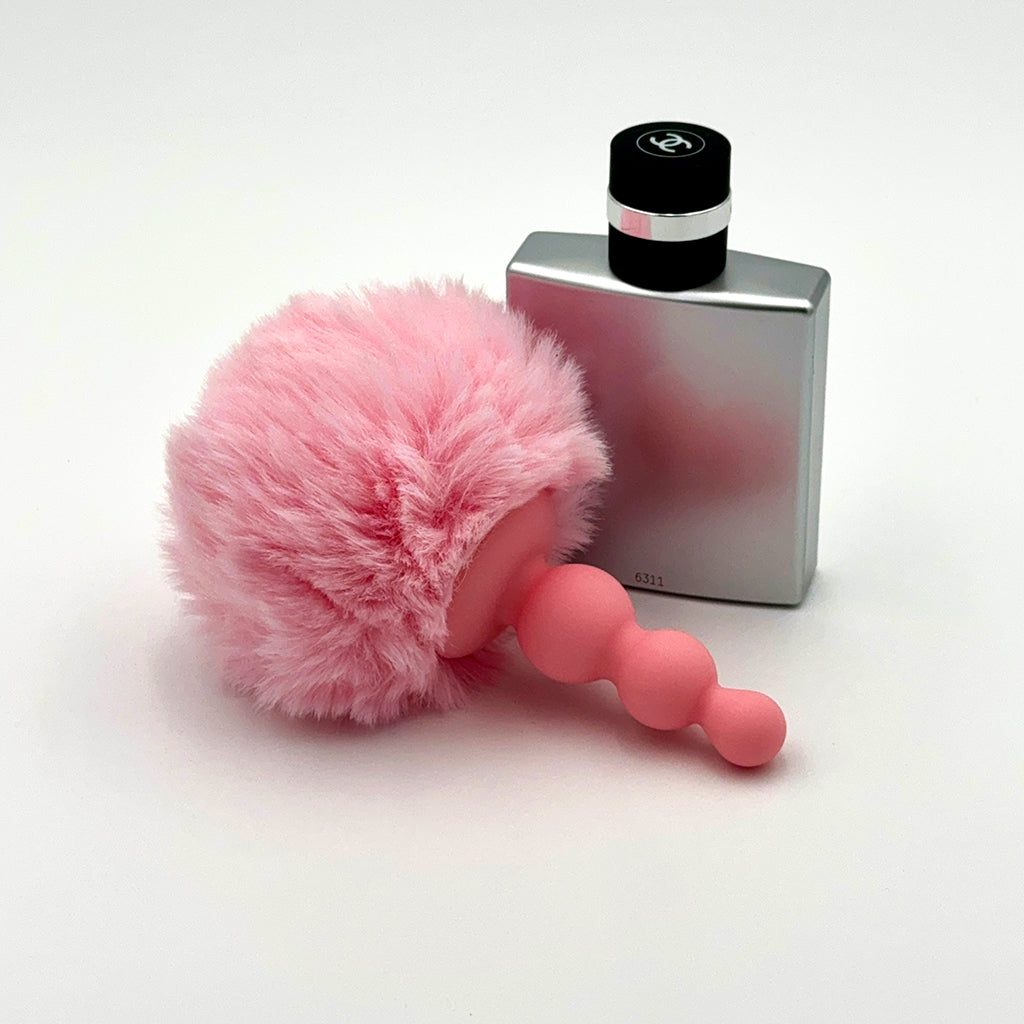 Comparison shot: Pink Anal Plug with Bunny Tail next to a stylish perfume bottle, highlighting the size for a perfect blend of pleasure and elegance.