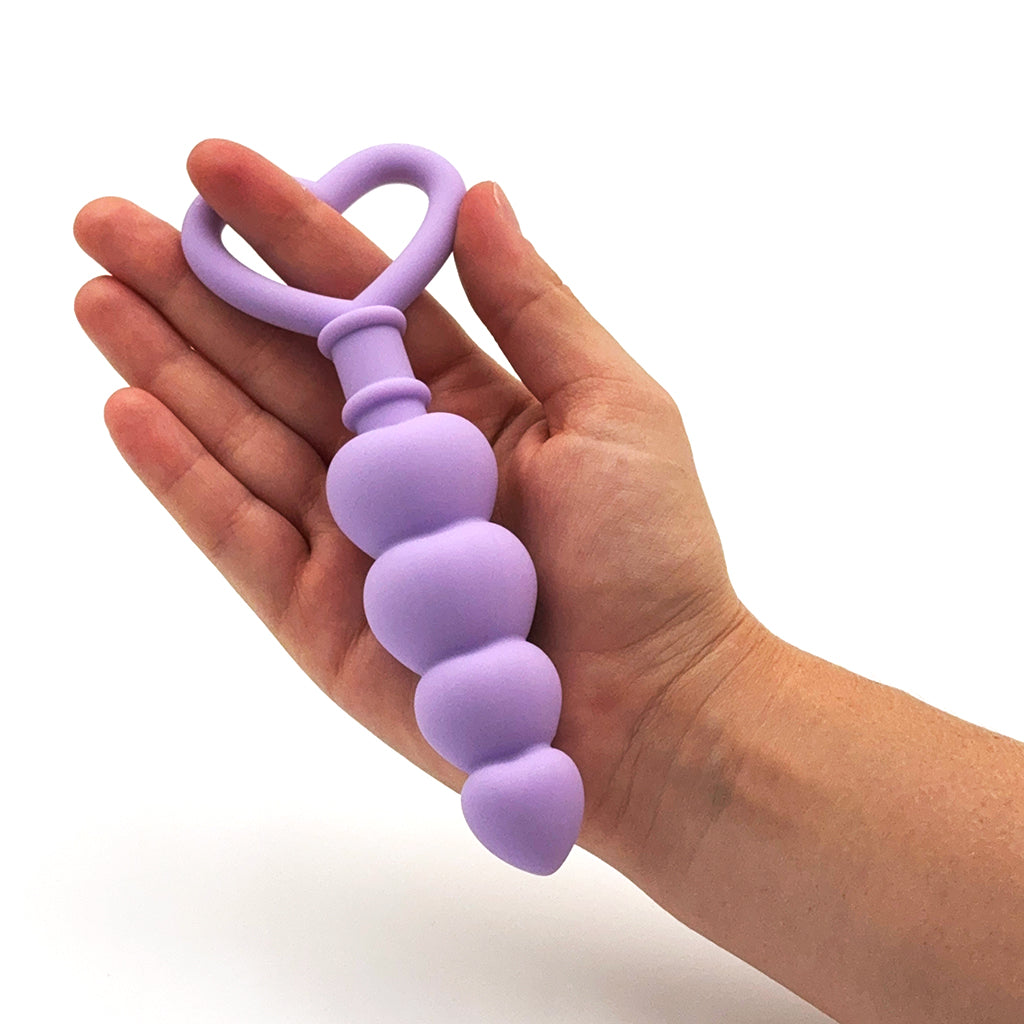Photo of Purple Beaded Butt Plug with Handle held in hand, demonstrating its size.